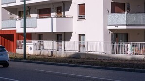 A multi-story residential building with balconies and a red roof.
