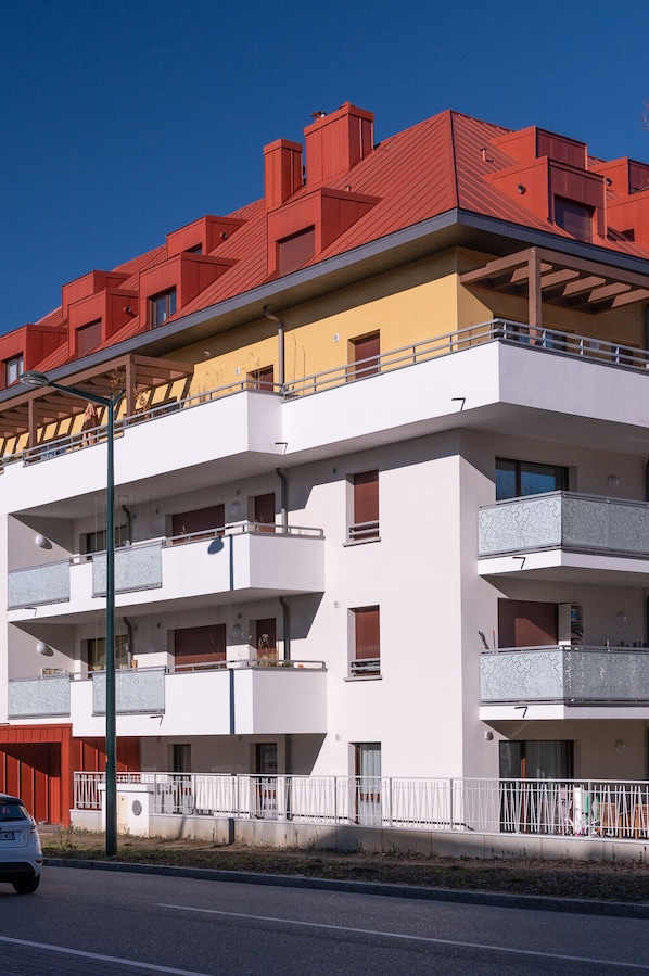 Un edificio residencial de varios pisos con balcones y un techo rojo.