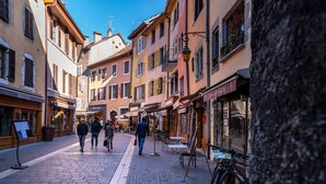 A cobblestone street lined with historic buildings, some with shops and cafes.