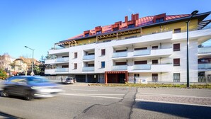 A multi-story building with balconies, a red roof, and a clear sky.