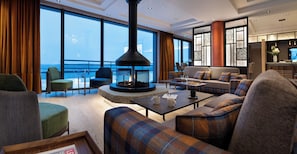 A modern living room with a fireplace, seating, and a view of the ocean. - MGM Hôtels & Résidences – Résidence Alpen Lodge (Montvalezan)