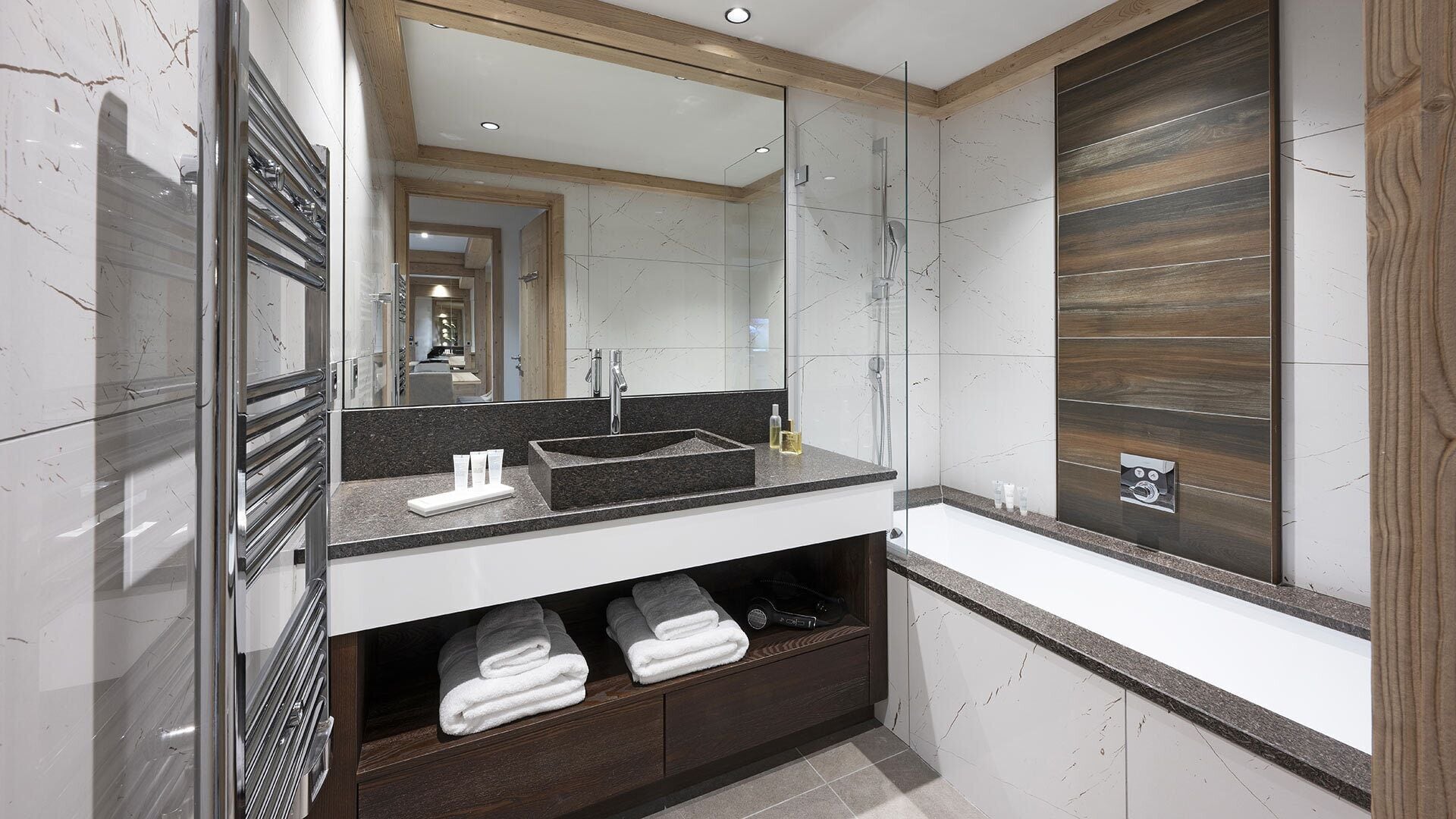 A modern bathroom with a large mirror, a sink, and a vanity with storage drawers.
