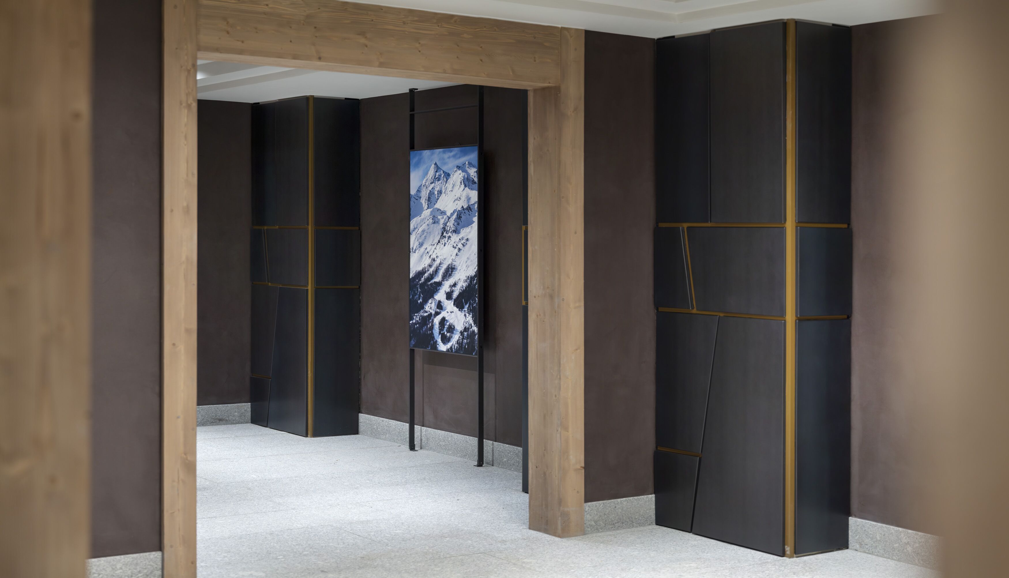 A hallway with dark walls and a large framed picture of a mountain.