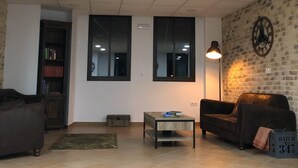 A living room with a sofa, a coffee table, and a bookshelf. - Benarrabá Hostel (Benarraba)