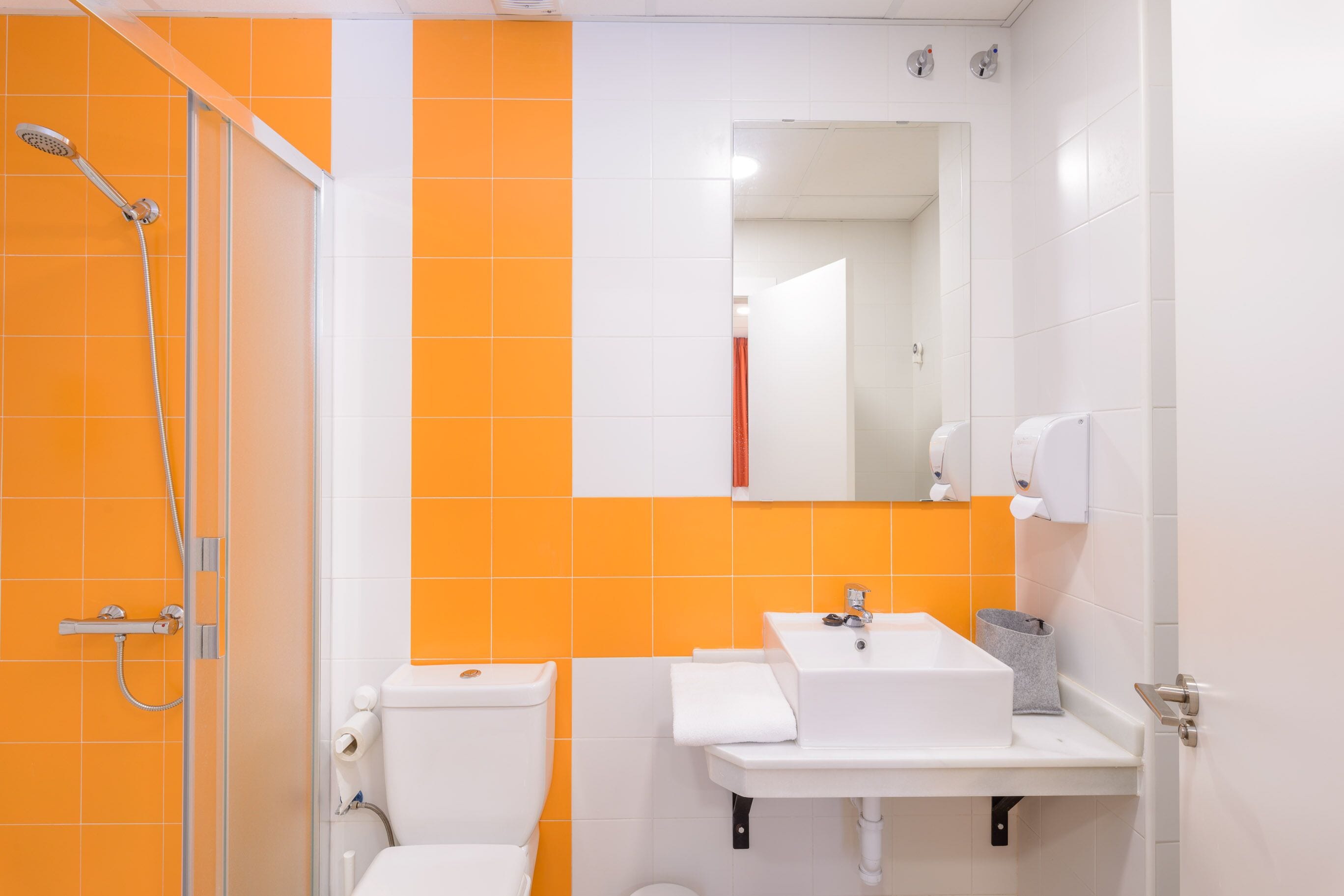 Un baño con ducha, inodoro, lavabo y espejo.