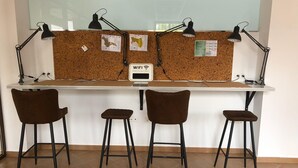A workspace with a corkboard, four brown chairs, and two black desk lamps. - Benarrabá Hostel (Benarraba)