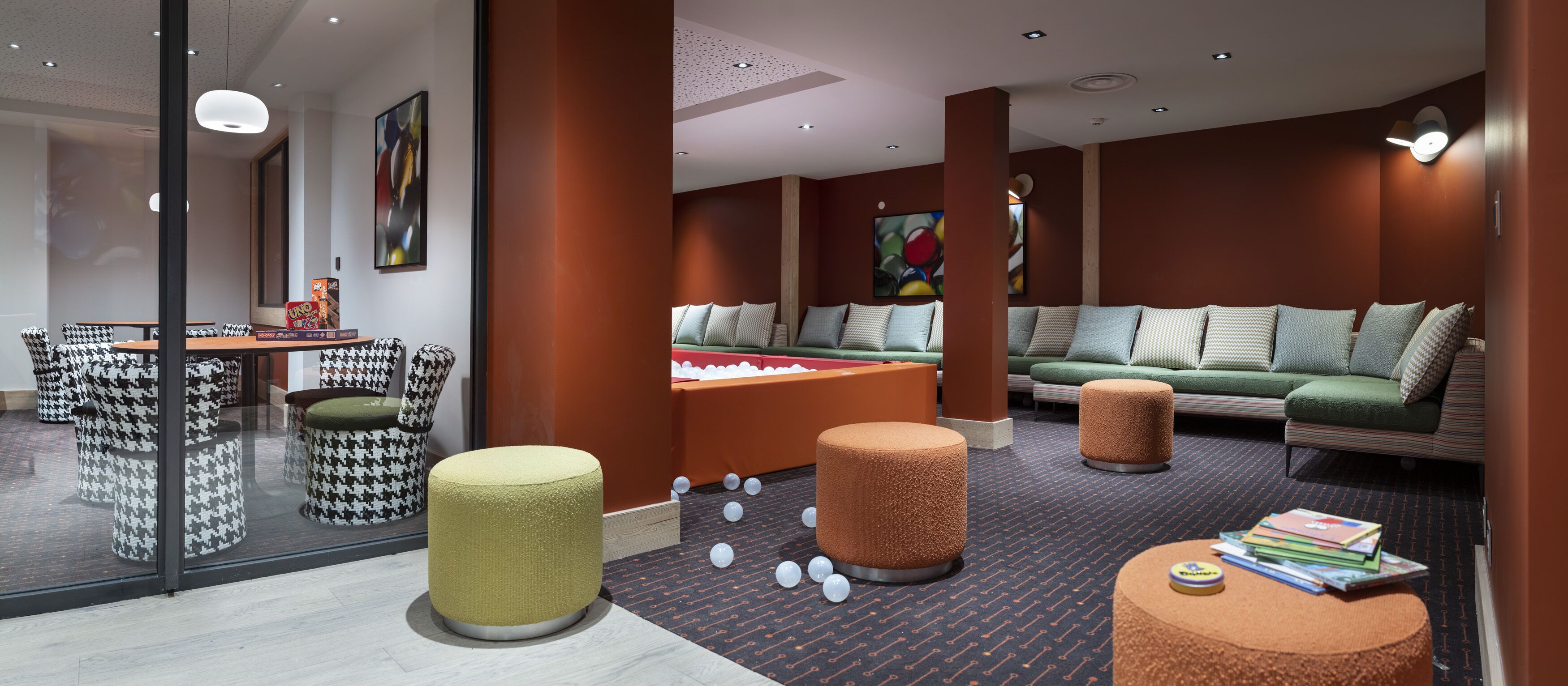 Een moderne lounge met een pooltafel, zachte zitplaatsen en een glazen scheiding.