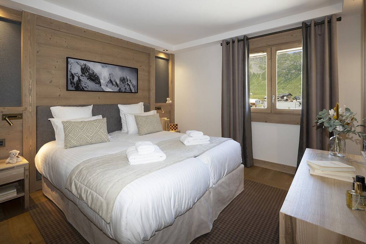 Ein Hotelzimmer mit einem großen Bett, einem Nachttisch mit Lampe, einem Fernseher und einem Fenster mit Vorhängen.