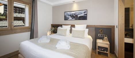 Una habitación de hotel con una cama grande, una mesita de noche, una ventana con cortinas y un cuadro enmarcado en la pared.