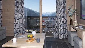 A modern room with a balcony, a dining area, and a seating area with a table set for breakfast. - MGM Hôtels & Résidences – Hôtel Alpen Lodge (Montvalezan)