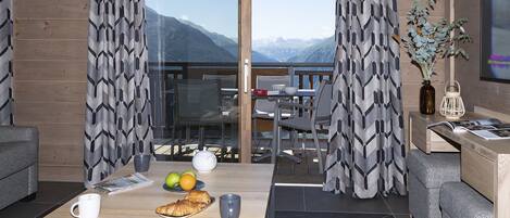 Una habitación moderna con balcón, zona de comedor y espacio de estar con mesa preparada para el desayuno.