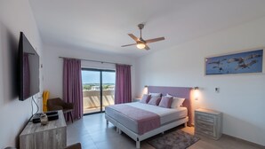 Un dormitorio moderno con cama, ventilador de techo, televisor, escritorio y silla.