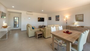 Una sala de estar moderna con un sofá, una mesa de comedor y un televisor.