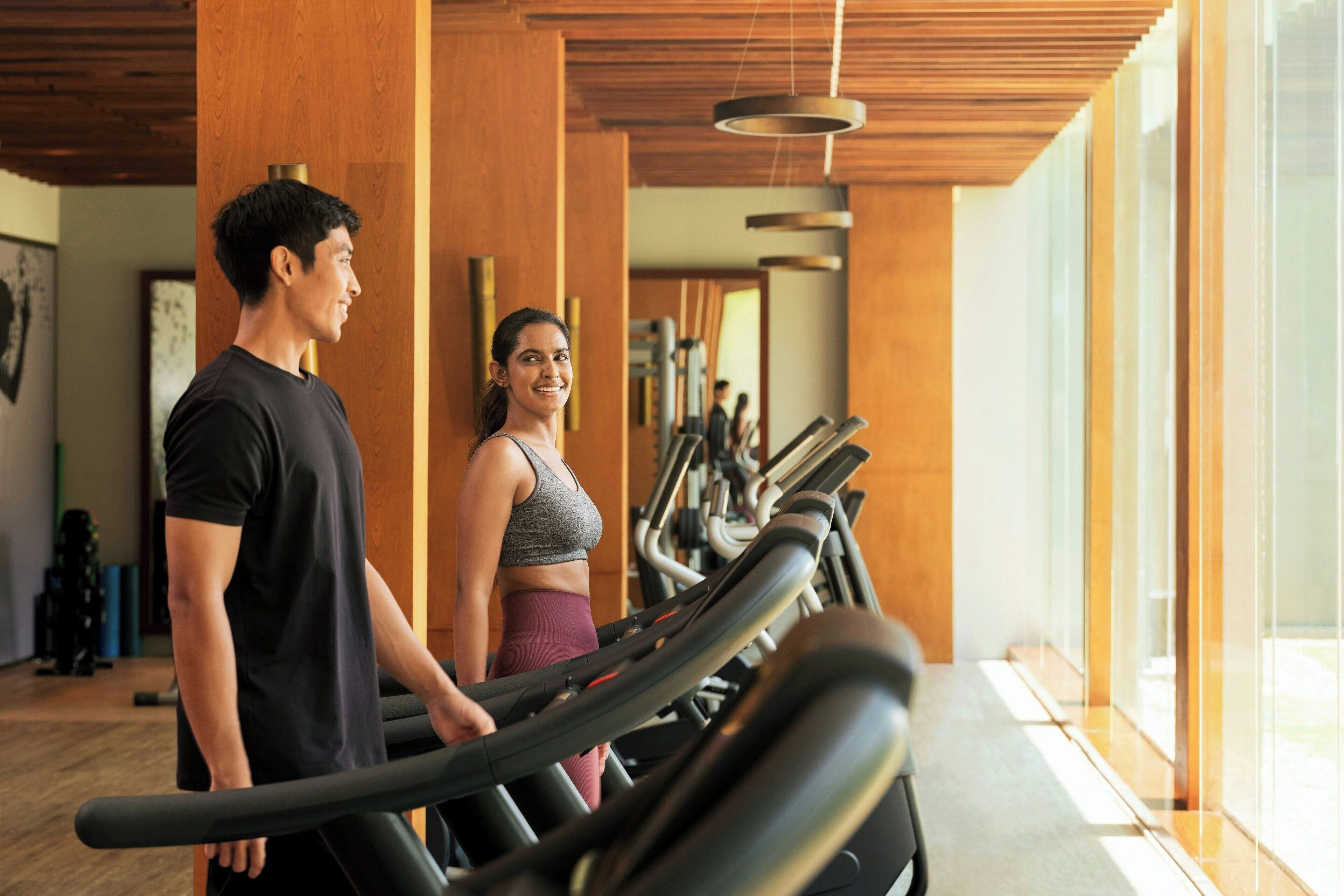 Une salle de sport équipée de tapis de course, de poutres en bois et d'appareils d'exercice.