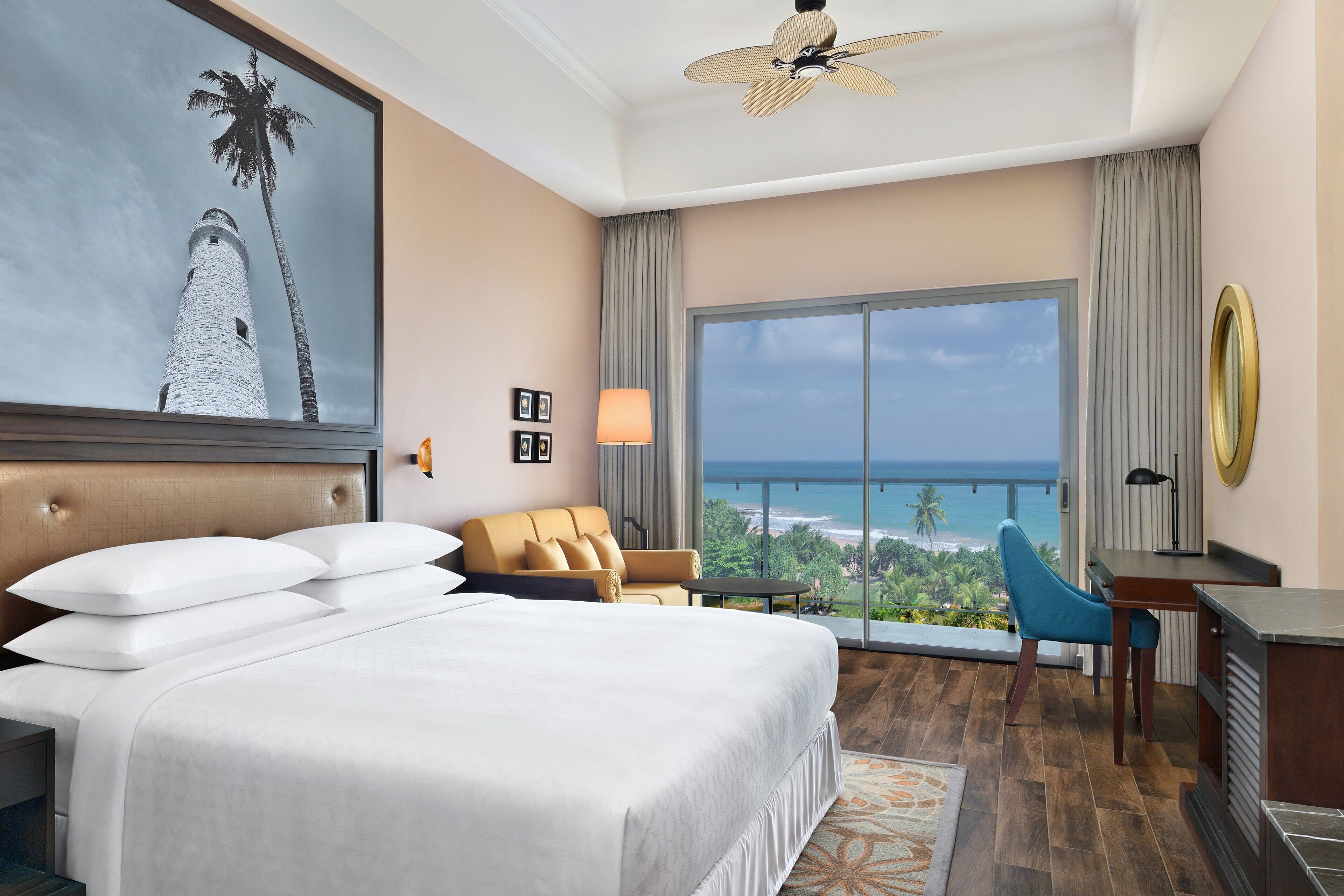 Een hotelkamer met een groot bed, een bank, een bureau en uitzicht op de oceaan.