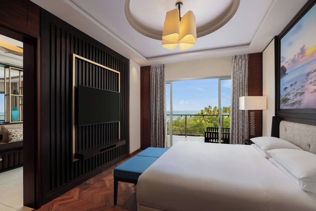 Ein Hotelzimmer mit einem großen Bett, einem Fernseher, einem Balkon mit Aussicht und einer Deckenleuchte.