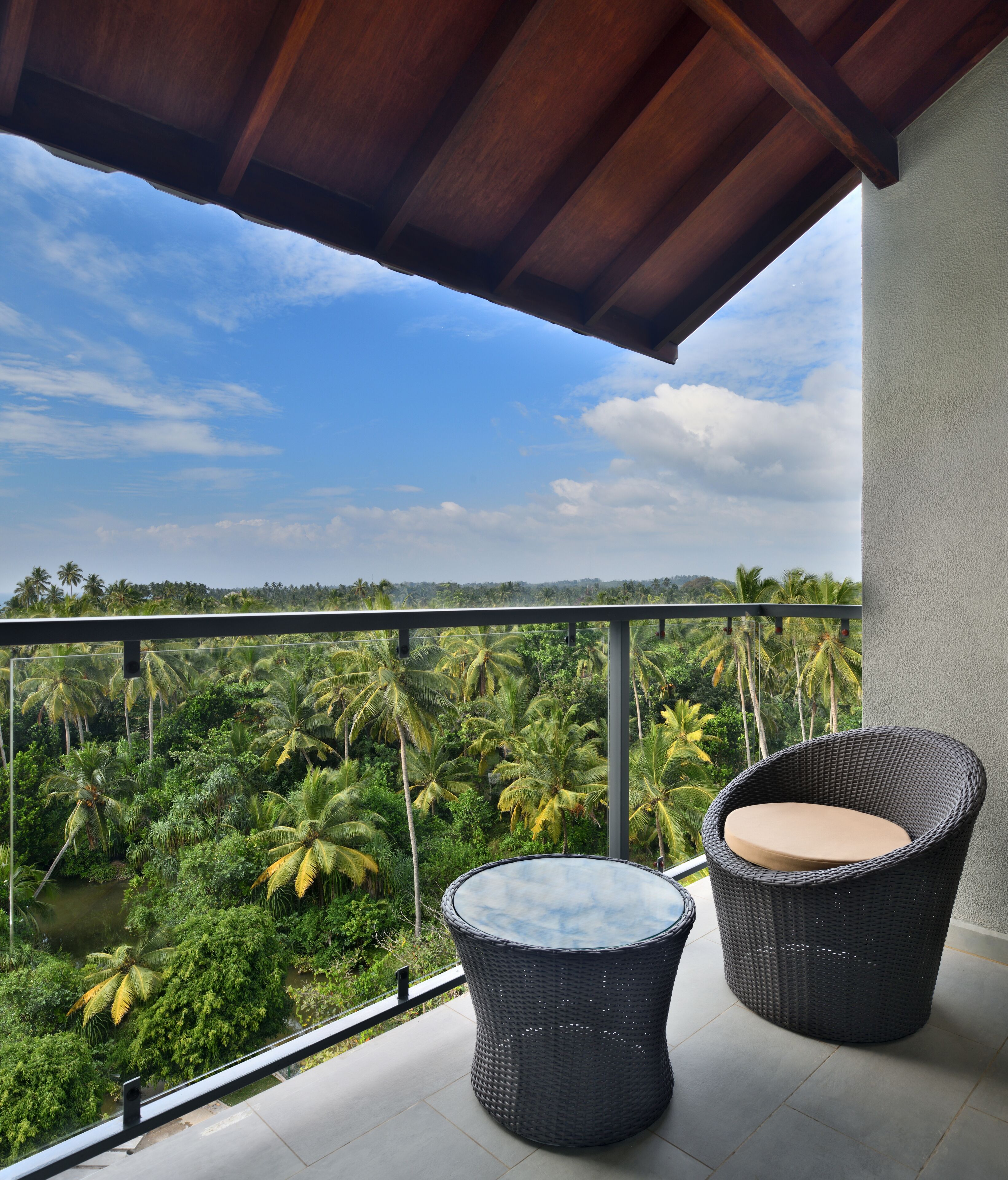 Un balcón con mobiliario de mimbre y vistas a un paisaje tropical.