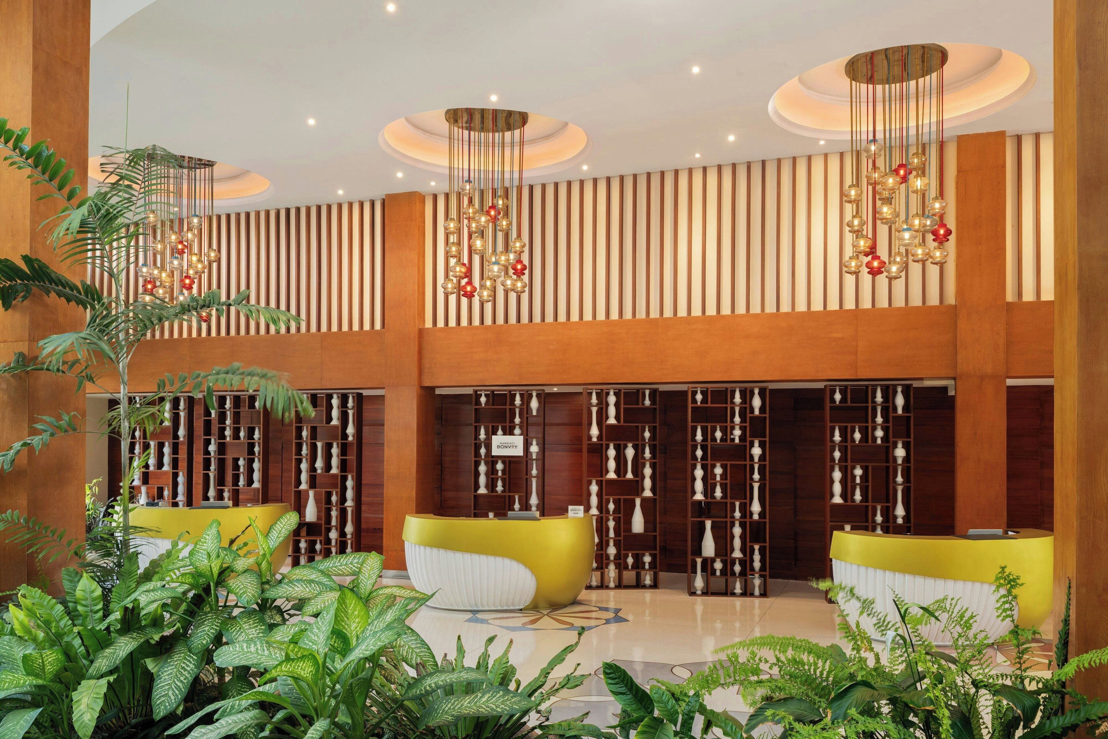 A lobby with a reception desk, vertical wooden paneling, and a chandelier.