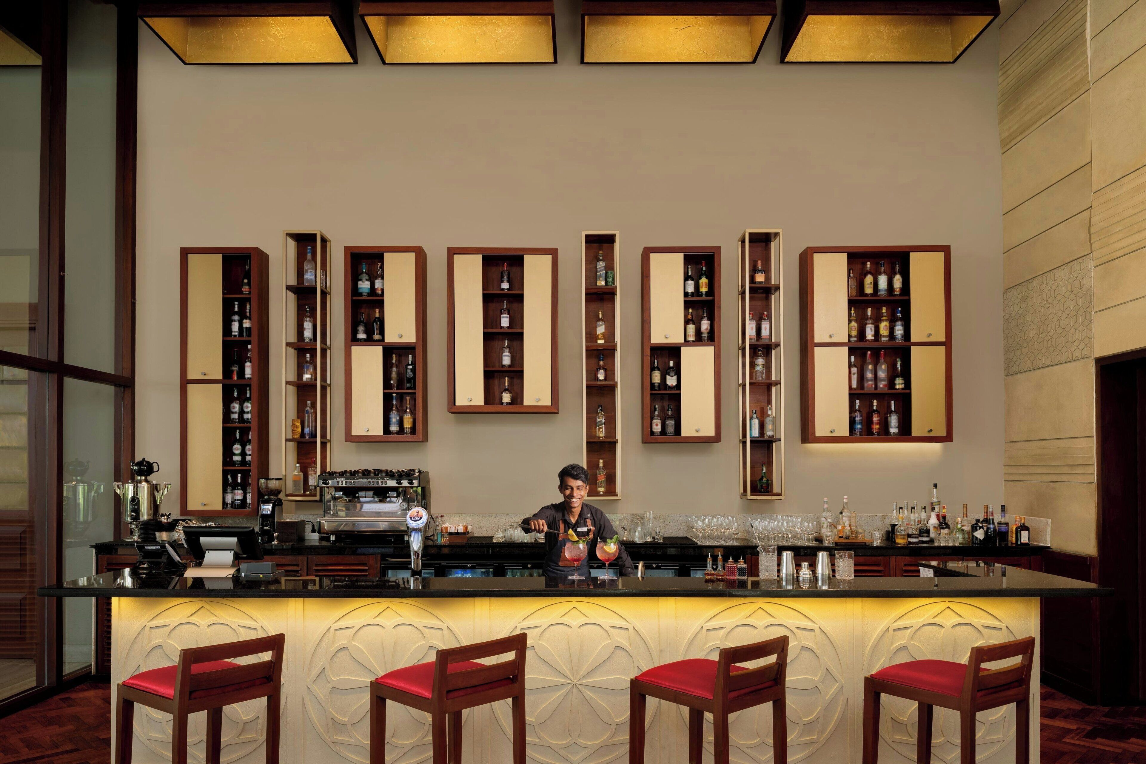 A bar area with a bartender, multiple liquor shelves, and bar stools.