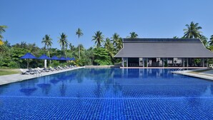 Une piscine aux carreaux bleus, avec des chaises longues et des parasols.