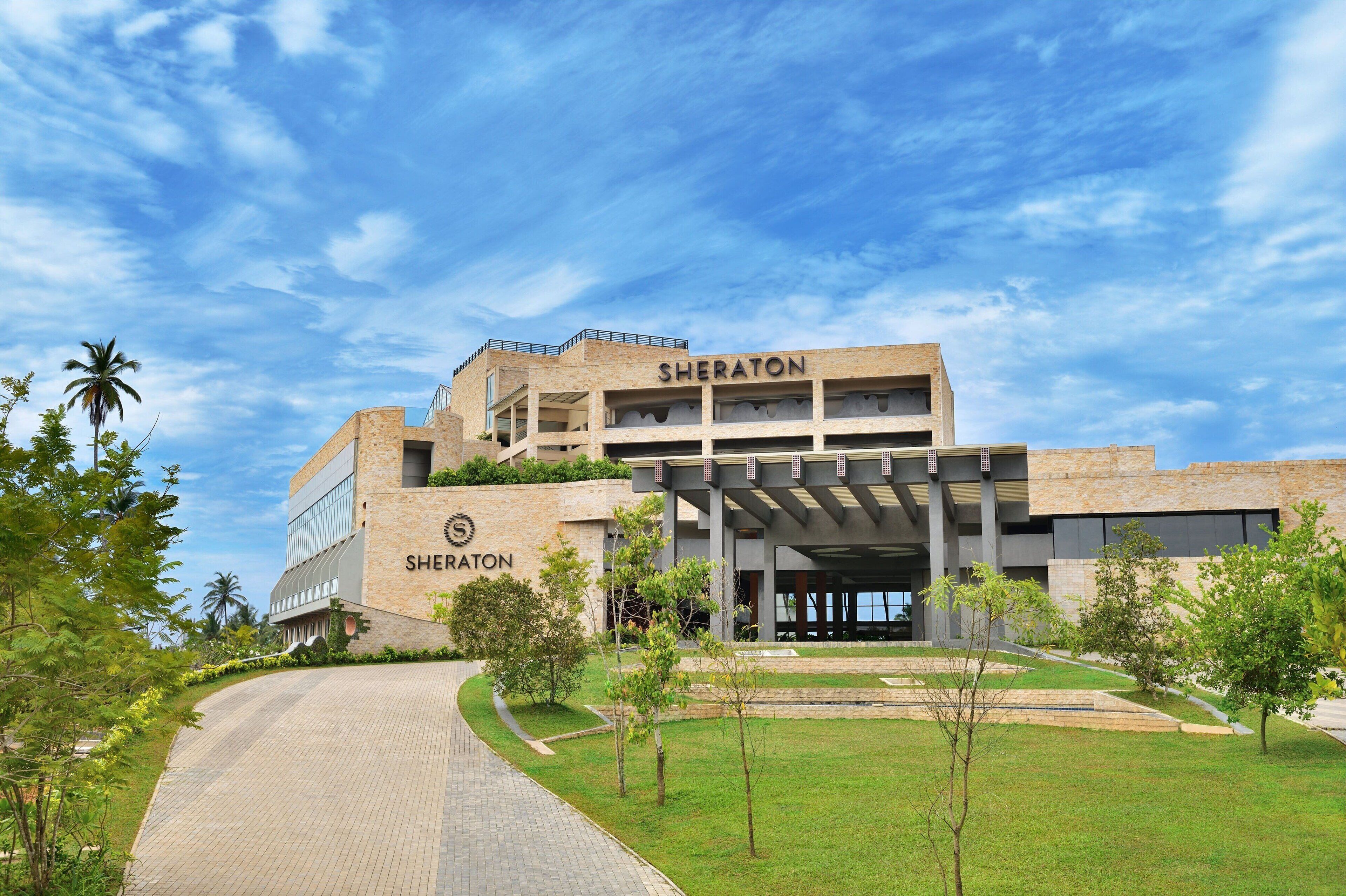 A Sheraton hotel with a modern architectural design, featuring a prominent entrance and a landscaped area with trees.