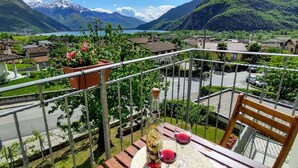 Un balcon avec une table, deux verres à vin et un vase de fleurs.