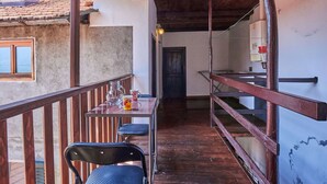 Un balcon avec une balustrade en bois, une table avec des chaises et une vue sur une montagne.