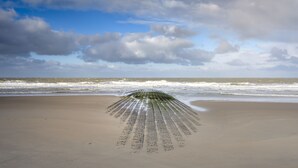 Een strand met een lange, smalle zandbank die zich in de oceaan uitstrekt.
