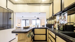 Een moderne keuken met een groot schiereiland, zwartbeige kastjes en uitzicht op de woonkamer.