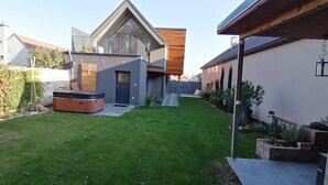 A modern house with a sloped roof, a wooden deck, and a small garden area.