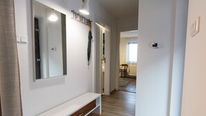 A hallway with a white bench, a mirror, and a coat rack with an umbrella.