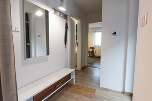 A hallway with a white bench, a mirror, and a coat rack with an umbrella.