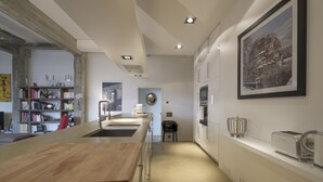 Una cucina moderna con un piano di lavoro in legno, elettrodomestici integrati e un quadro con una veduta cittadina sulla parete.