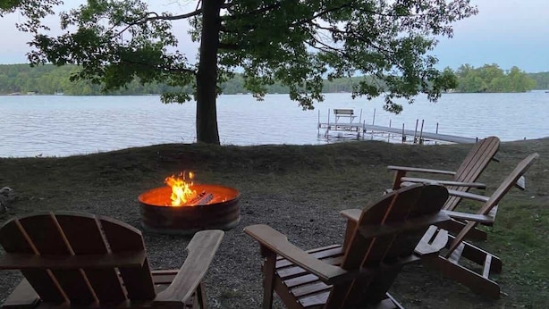 Un cadre idyllique au bord du lac, avec un foyer et des fauteuils Adirondack.