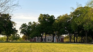 A house with a front lawn and trees in the background. - Texas Ranch House on 10 acres near Lake Ray Roberts! (Pilot Point)