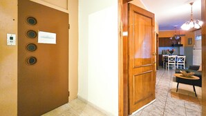 A hallway with a wooden door, a light switch, and a note on the door. - Hotel Exarhos (Katerini)