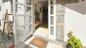 A hotel entrance with a stone facade, a wooden bench, and a potted plant. - Hotel Exarhos (Katerini)