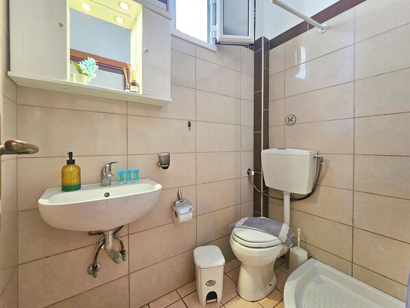 A small bathroom with a sink, toilet, and shower. - Hotel Exarhos (Katerini)