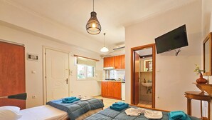 A hotel room with two beds, a TV, a kitchen area, and a bathroom. - Hotel Exarhos (Katerini)
