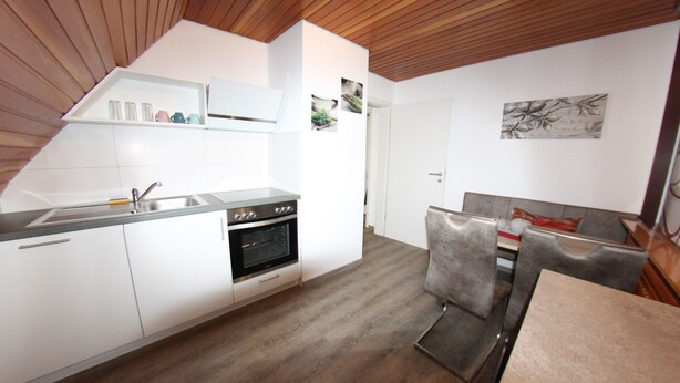 A modern kitchen with white cabinets, a built-in oven, and a wooden ceiling. - Welcome to the Trude house (Wulmeringhausen)