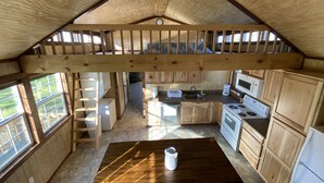 Een ruime keuken met houten kastjes, een centraal eiland en een vide met een houten leuning.