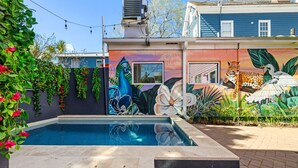 Ein Swimmingpool mit Wandmalerei, ein Backsteinweg und ein Gebäude mit Fenster.