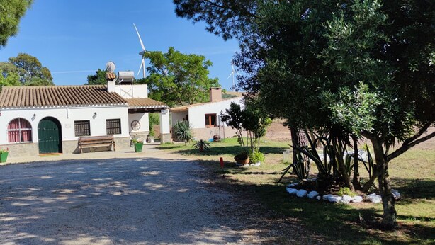 A building with a tiled roof, a green door, and a bench in front. - RURAL HOUSE TO ENJOY NATURE (Medina-Sidonia)