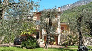 A two-story building with a stone facade, surrounded by olive trees and potted plants. - Cosy apartment for 3 guests with WIFI, TV, balcony and pets allowed (Malcesine)