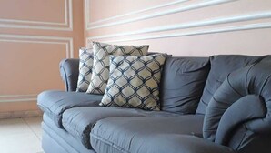 Ein graues Sofa mit gemusterten Kissen vor einer Wand mit geometrischen Paneelen.