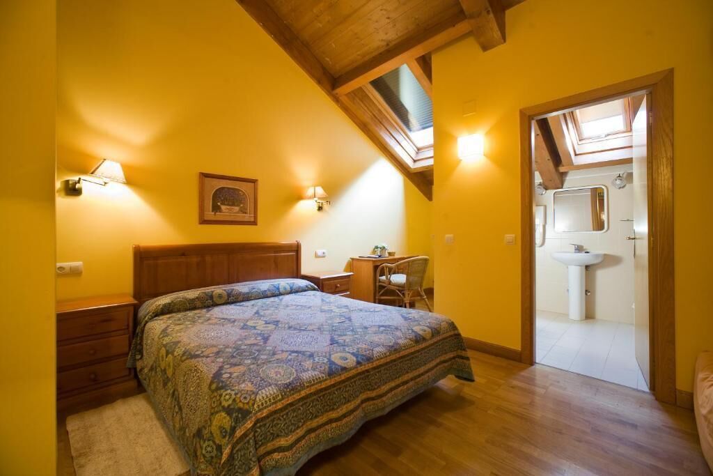 Une chambre à coucher avec un grand lit, un bureau, une chaise et une lucarne.