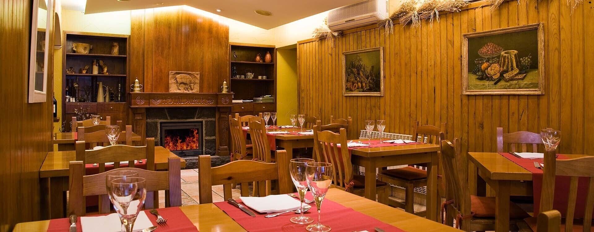 Un restaurante acogedor con paredes de madera, una chimenea y mesas dispuestas para comer.