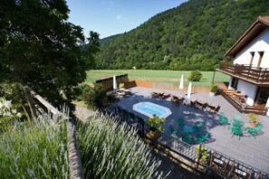 A rooftop patio with a hot tub, outdoor seating, and a view of a forested mountain. - Hostal Salazar (Oronz)
