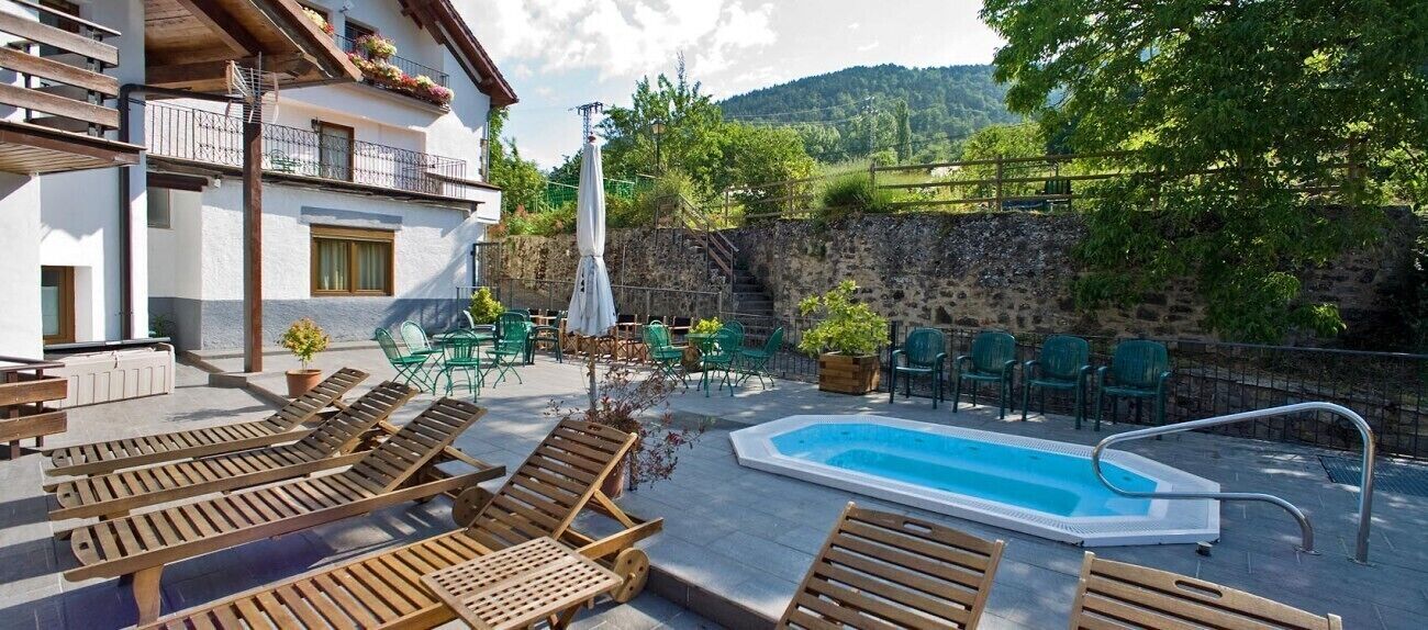 A poolside area with wooden loungers, a small pool, and outdoor seating.