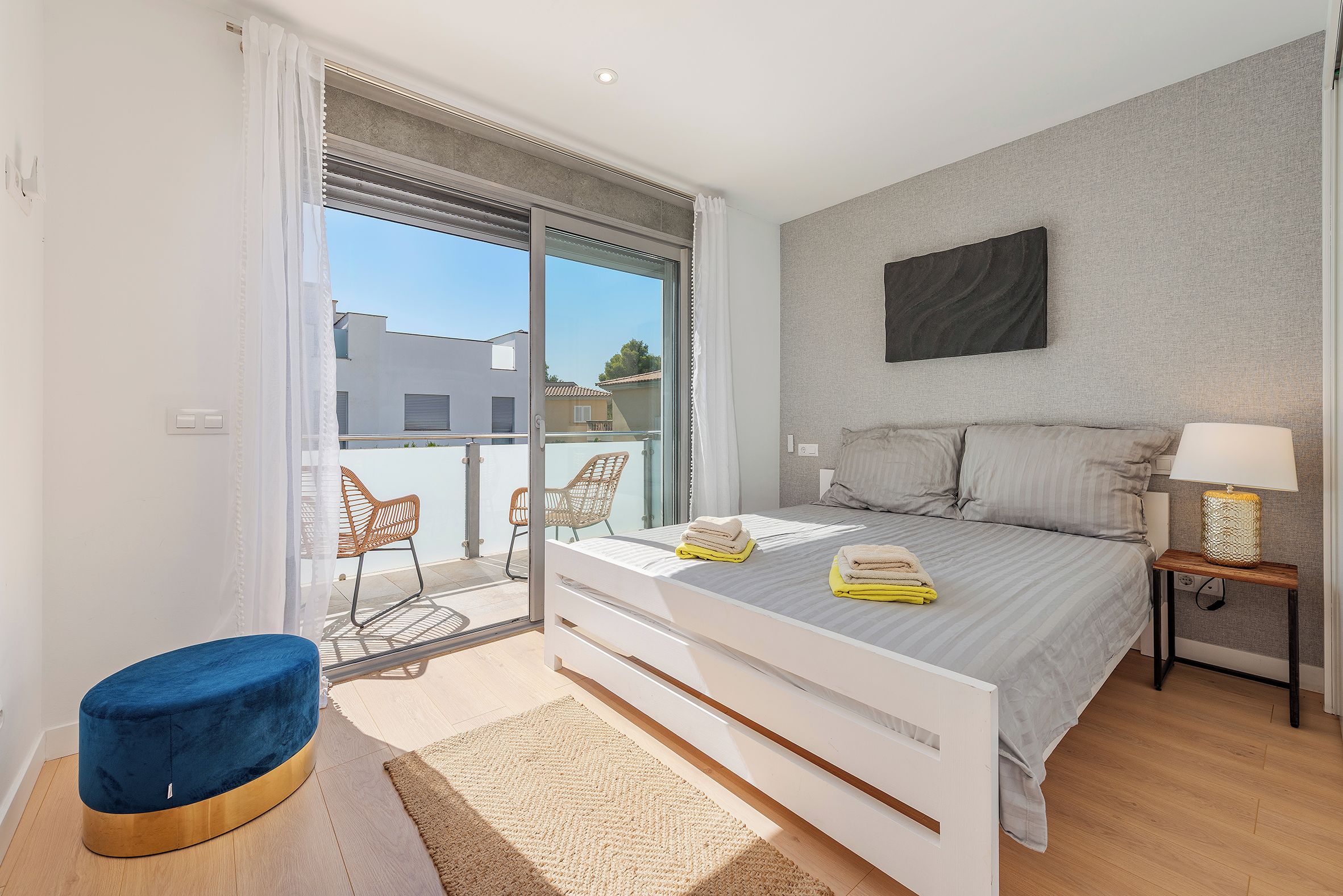 A modern bedroom with a bed, bedside table, and a view of the outside.